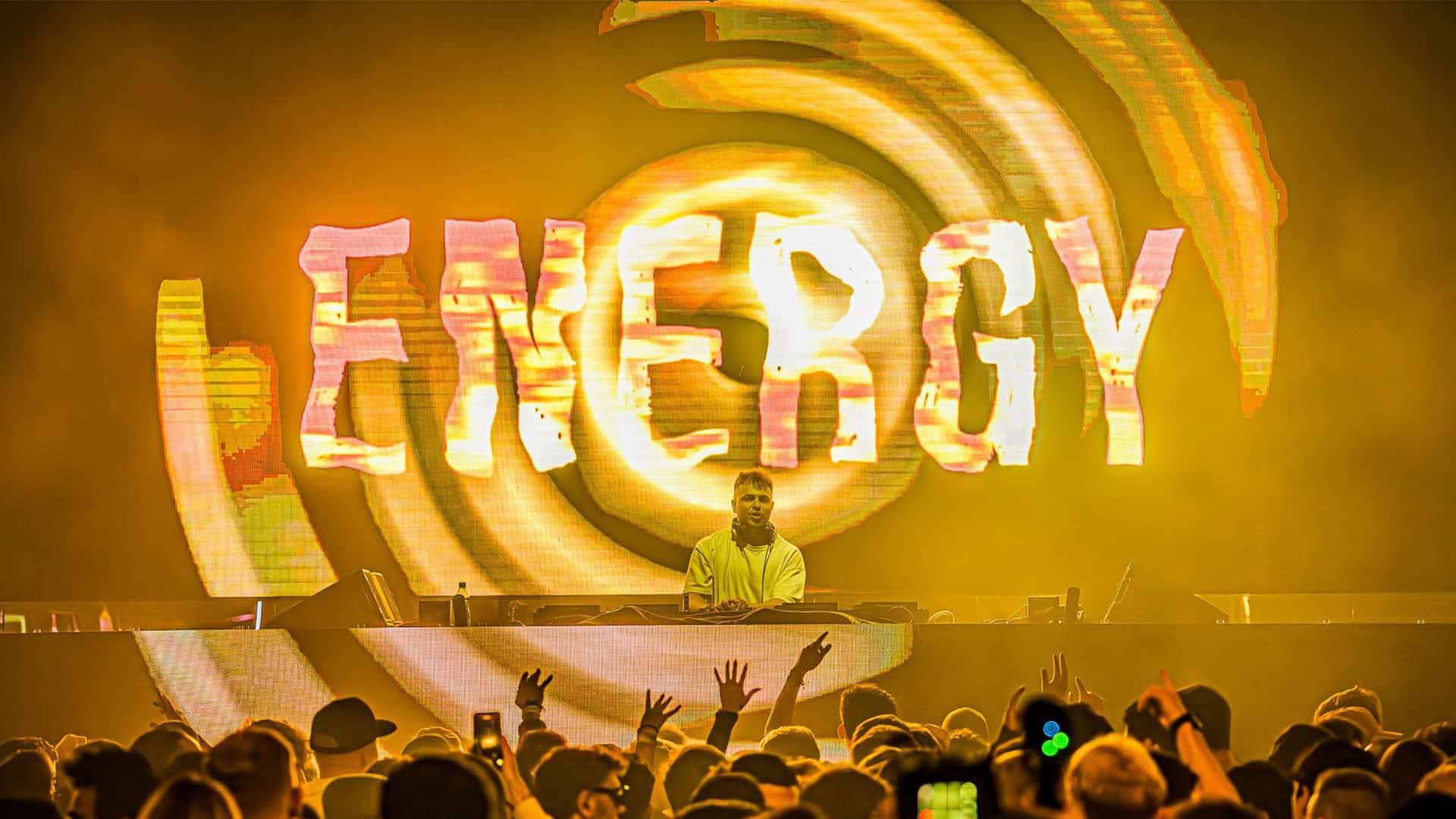 ENERGY stage visual in yellow with a DJ performing in front of the crowd