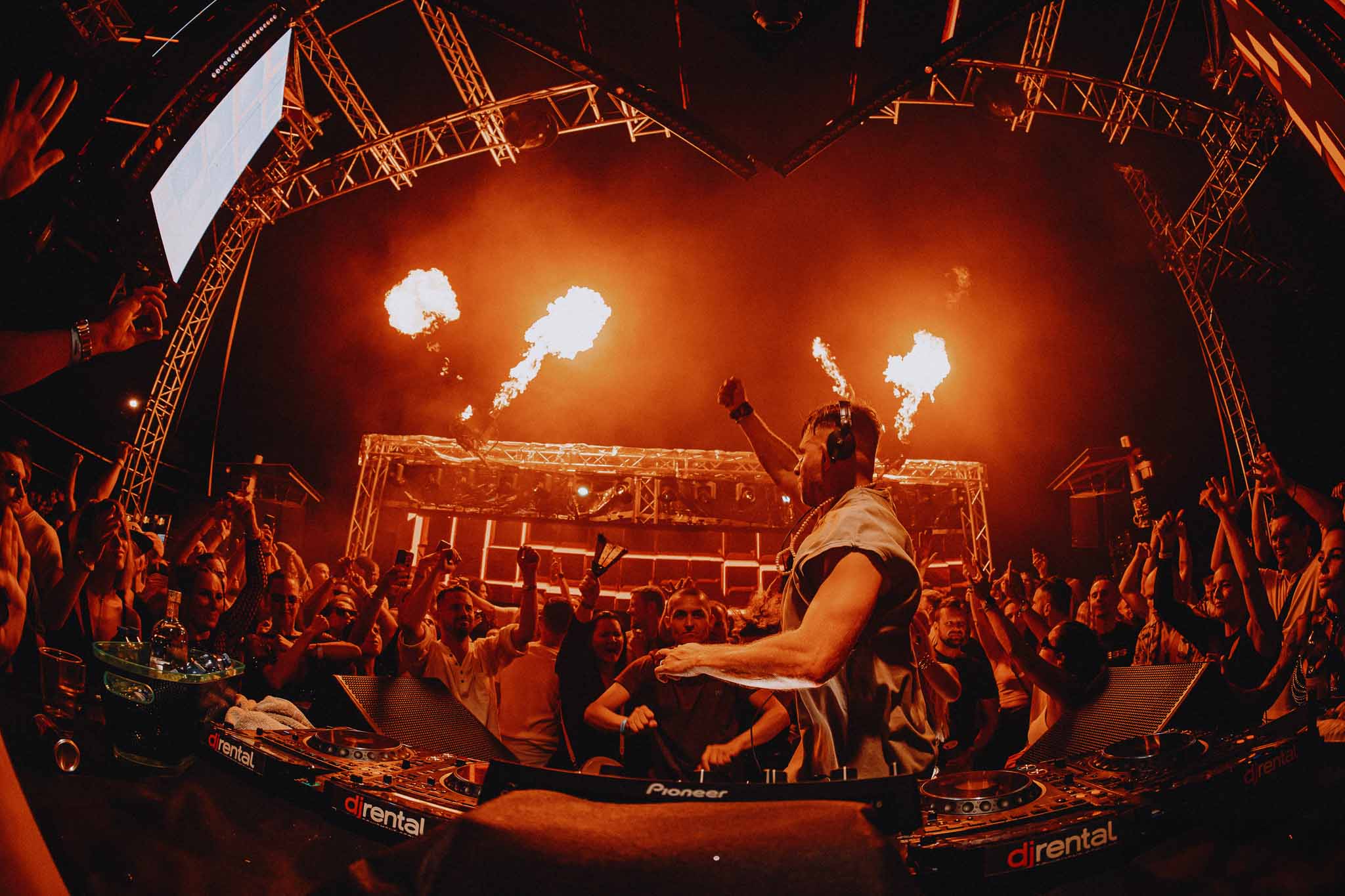 DJ EKG performing with flame effects on stage, fisheye view of the crowd