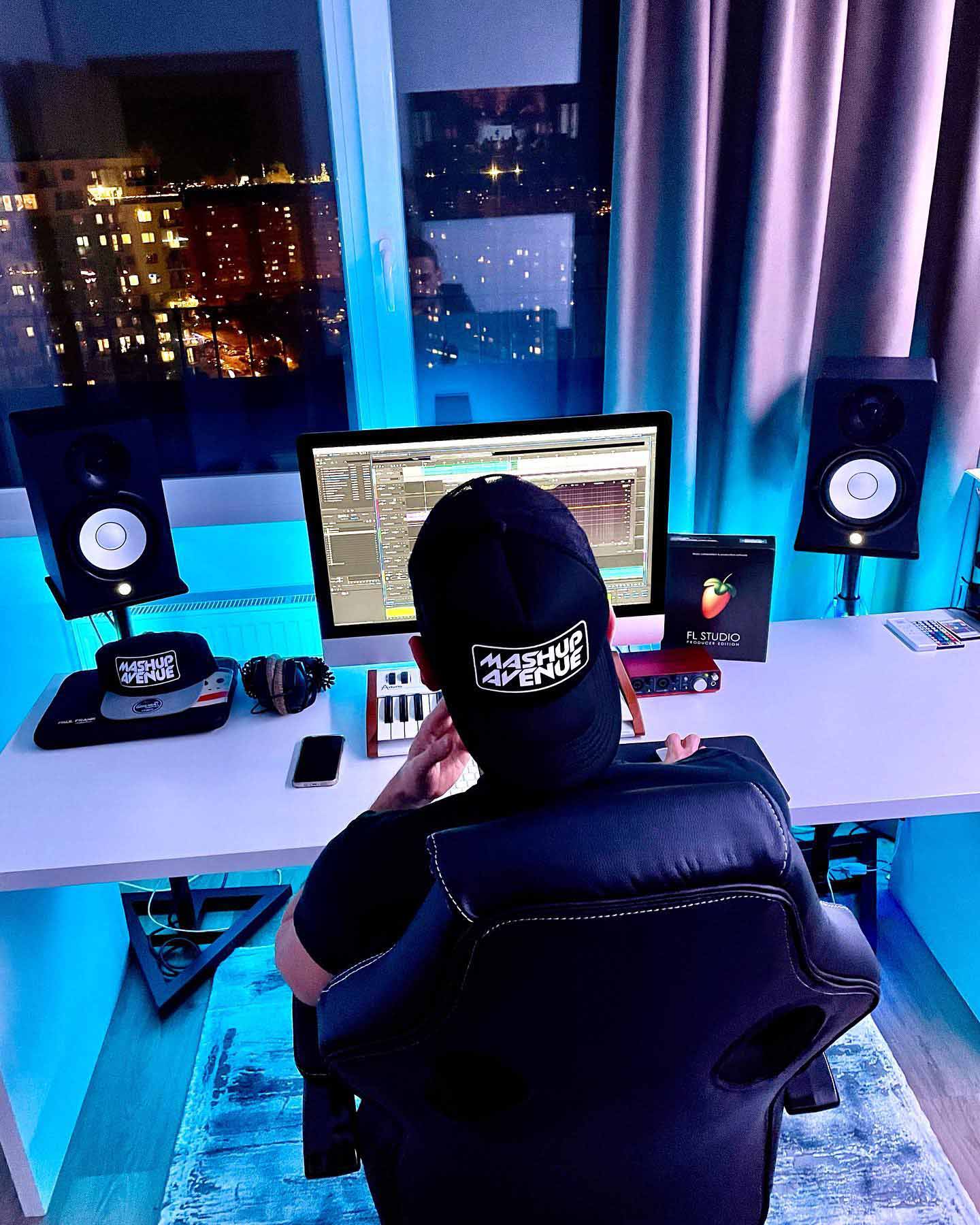 Producer at a studio desk with monitors and a night city view, JDC studio session